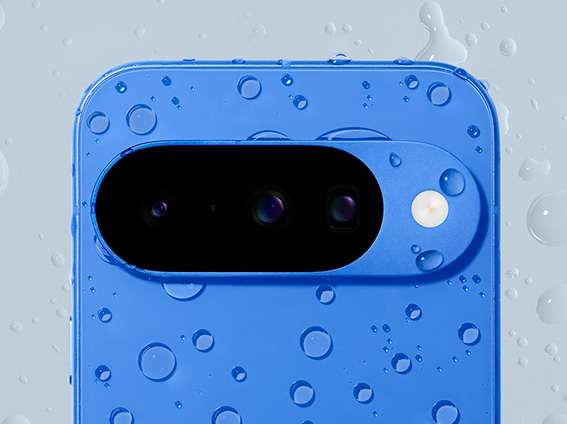 Image shows a Pixel 10 in indigo covered in warter drops 