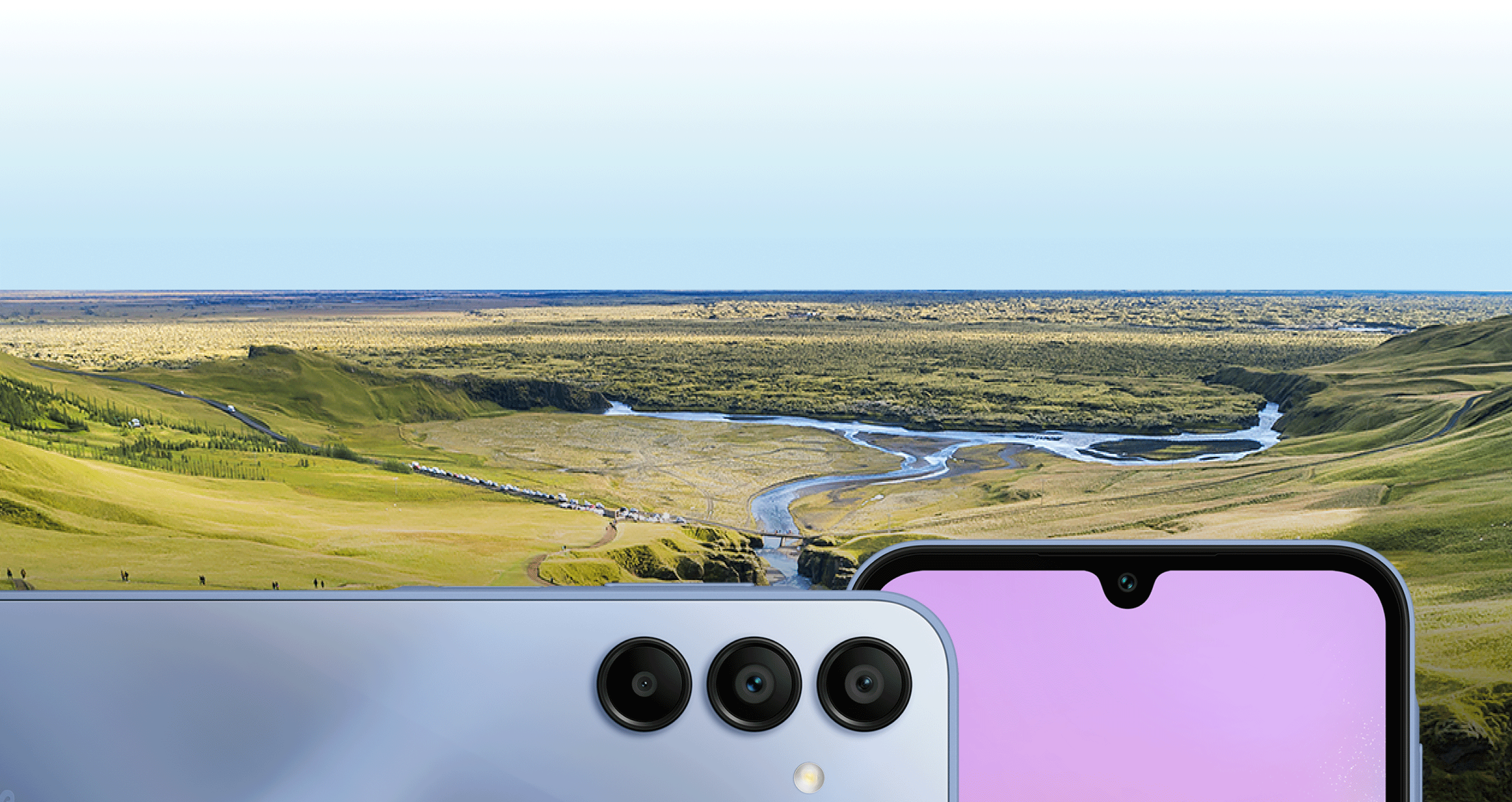 Image of a green field with a river and in front the phone from it's two sides displaying the cameras.