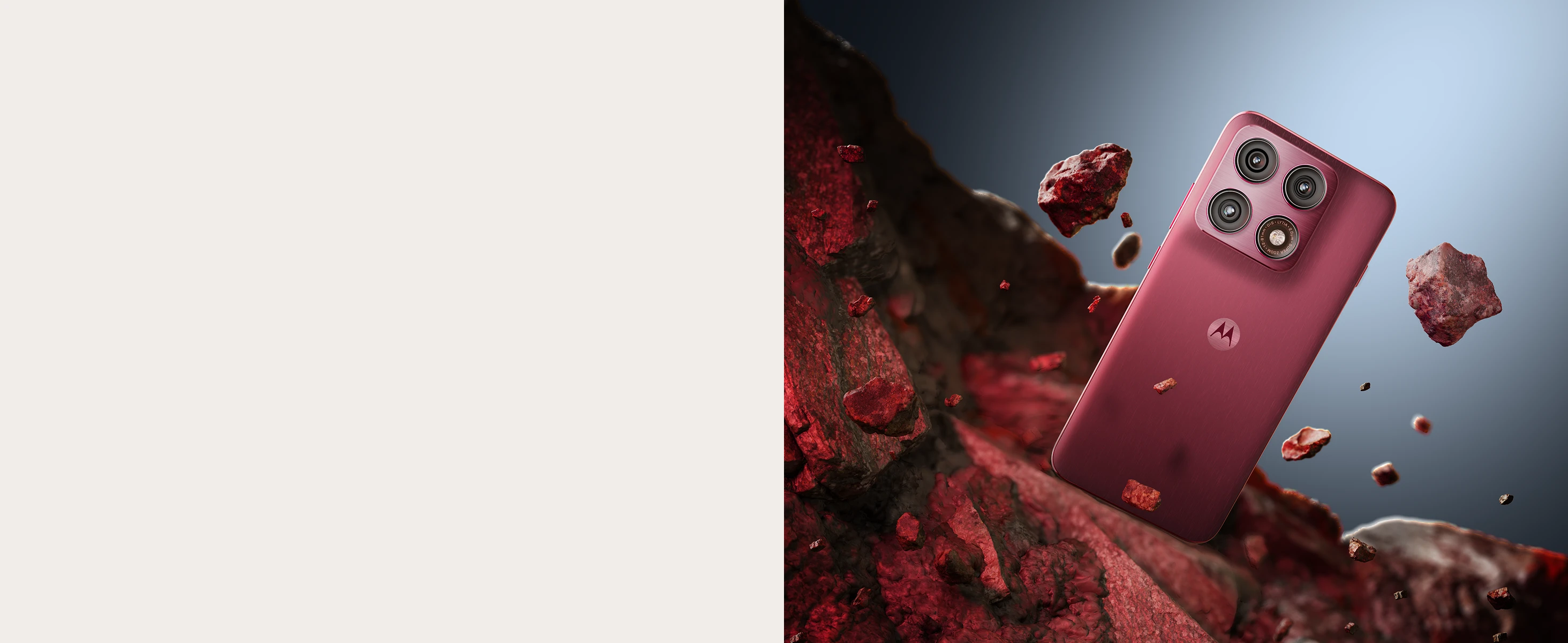 A red Motorola smartphone with four cameras floats among reddish rocky fragments against a bluish gradient background.