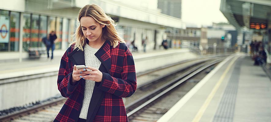 Woman at Train Station Texting on Mobile Phone