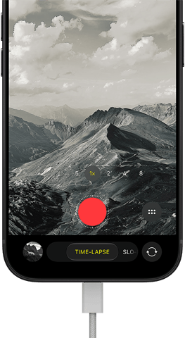 iPhone 18 Pro, front exterior, displaying a mountainous landscape, with the camera mode overlay in Time-Lapse mode, with charging cable attached to charging port